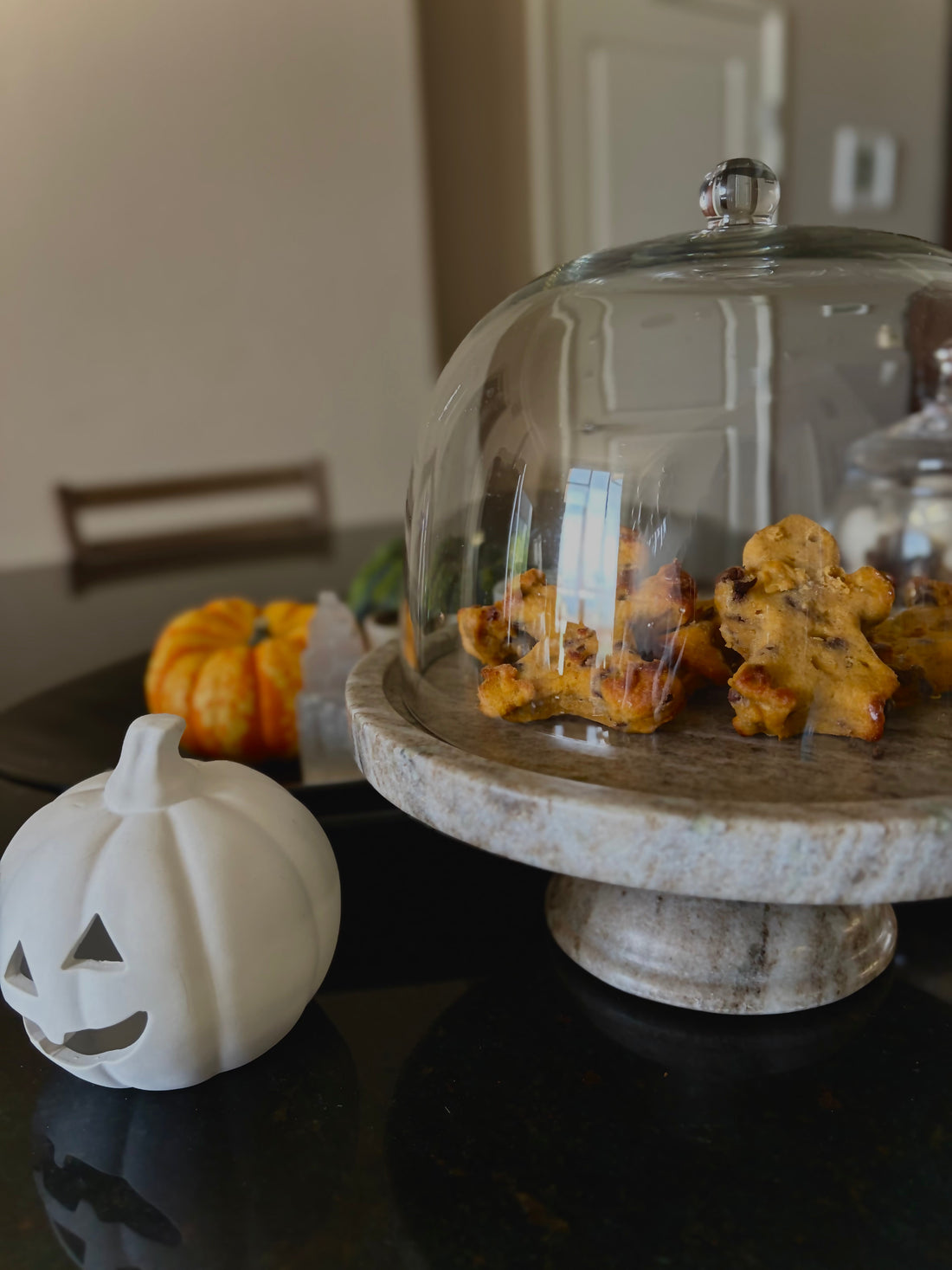 Pumpkin-chip chickpea muffins shaped like little gingerbread people on a marble cake stand with mini pumpkins